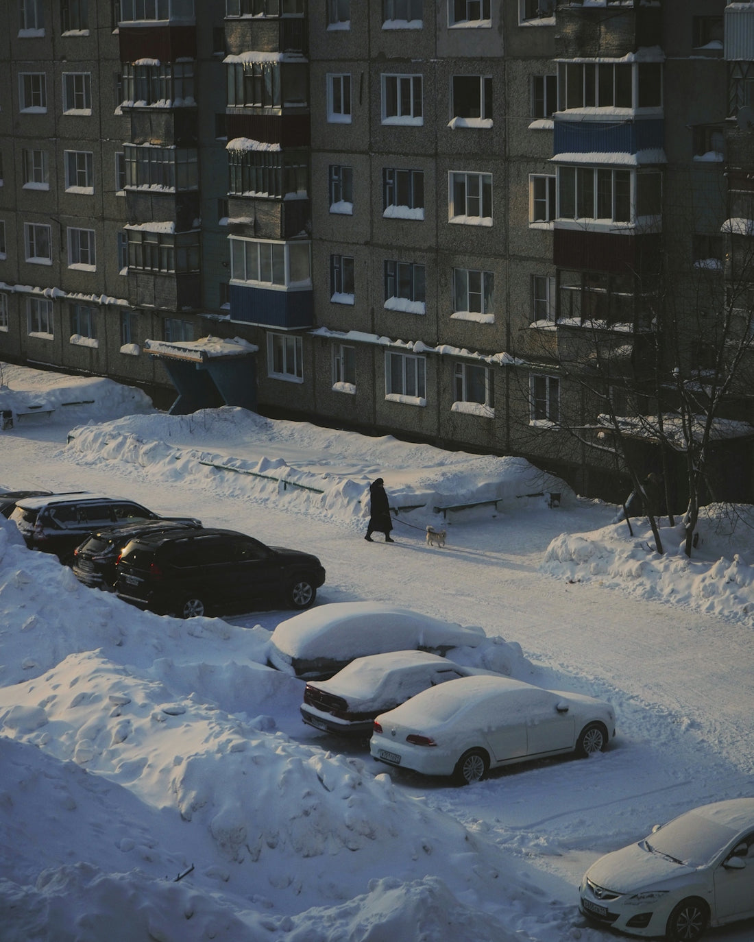 white sedan on snow covered road near building during daytime