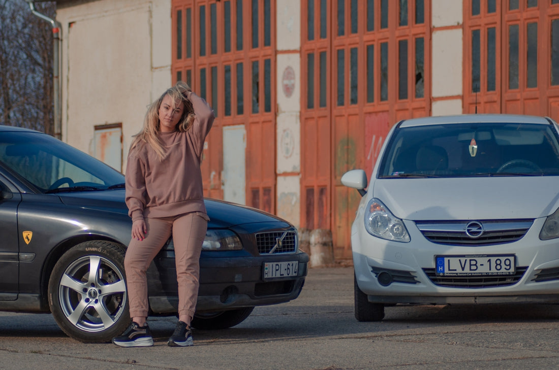 woman in brown leather jacket standing beside blue bmw car during daytime
