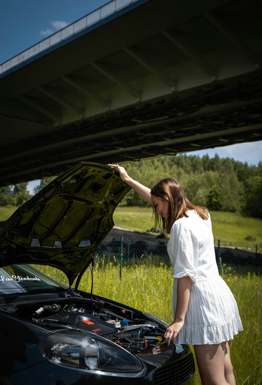 woman in white dress standing beside black car during daytime