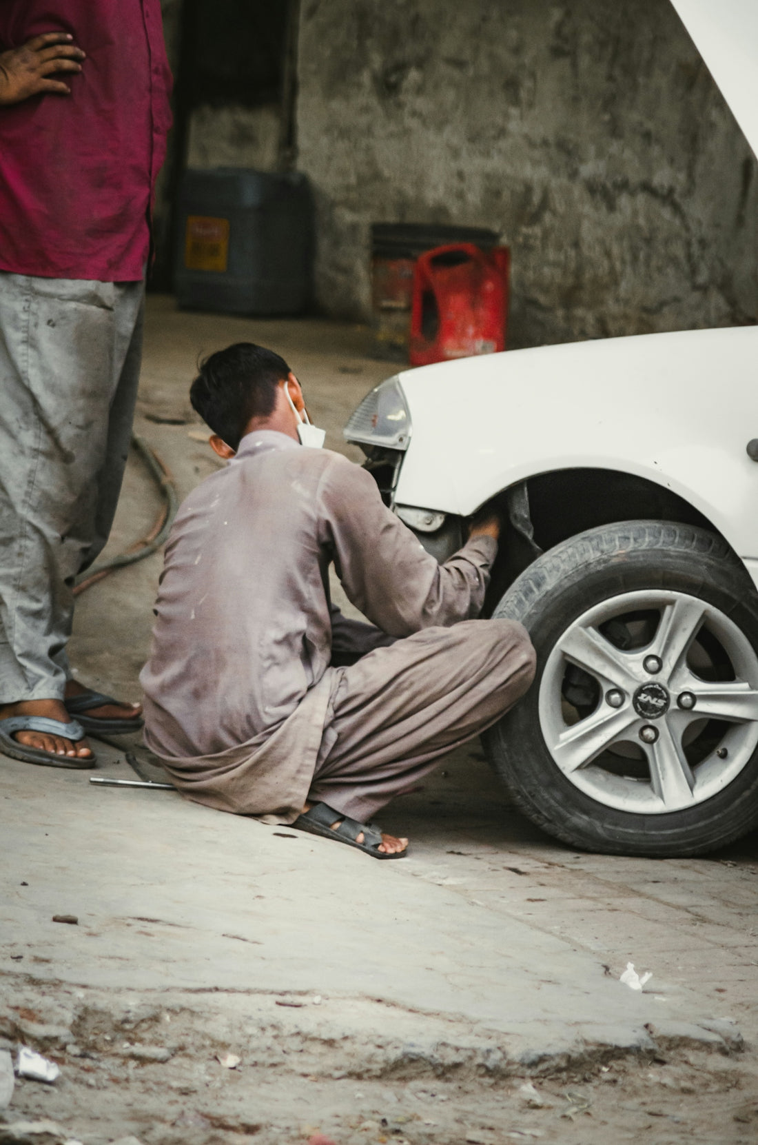 man in gray thobe sitting on white car