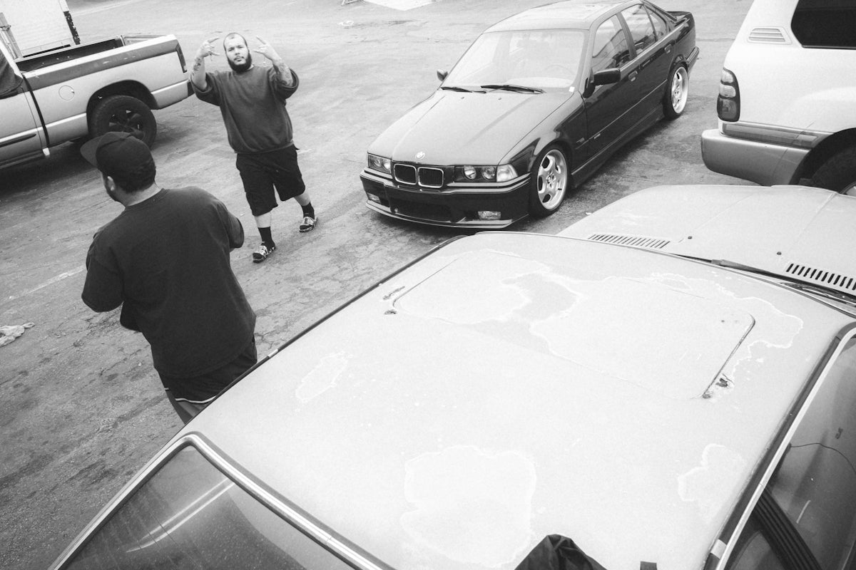 a couple of men standing next to a parked car