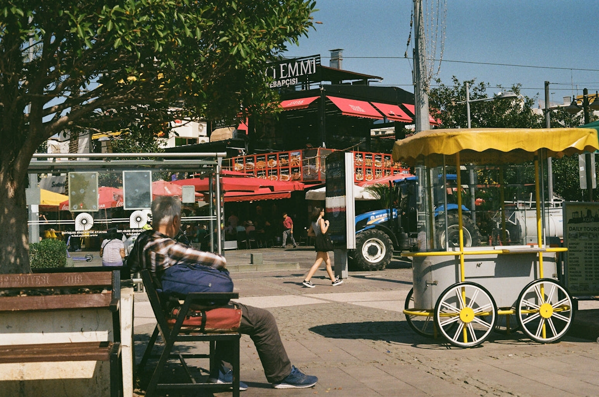 a man sitting on a bench next to a cart