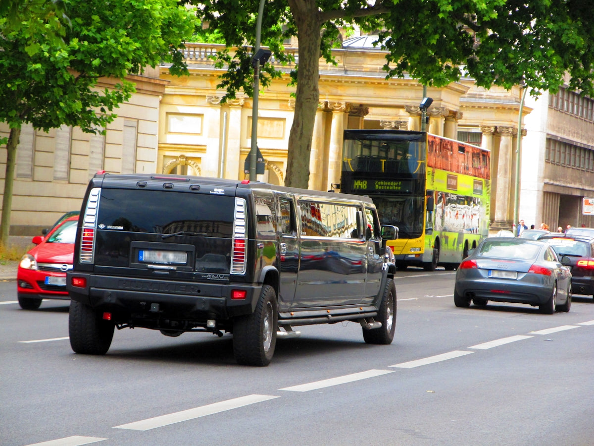 A black truck driving down a street next to tall buildings