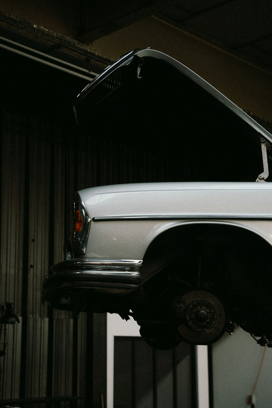 A white car is being worked on in a garage