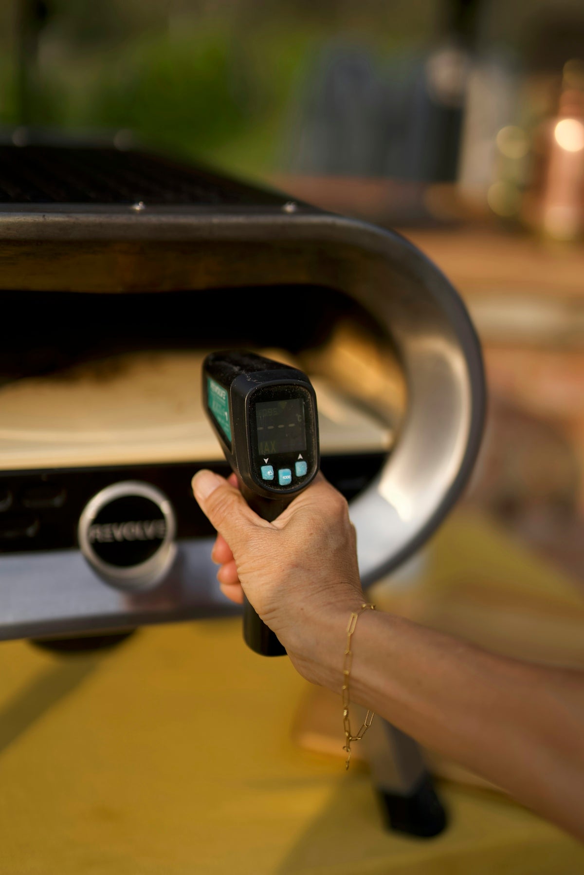 A person holding a cell phone in front of a grill