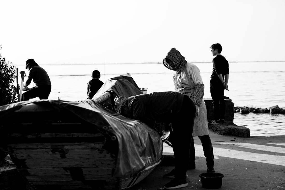 Fishermen are working on their boat near the ocean.