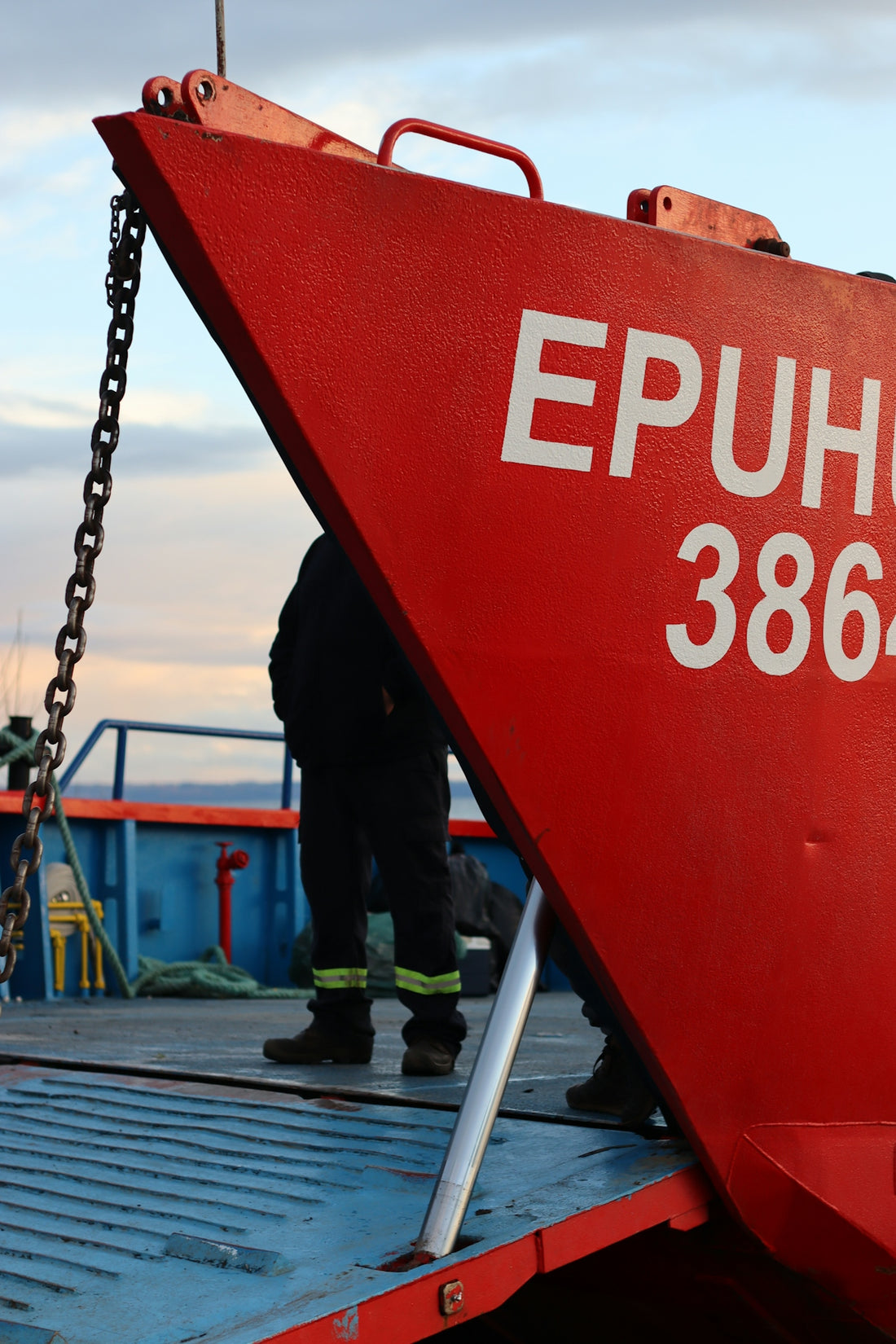 A red boat with person standing on board.