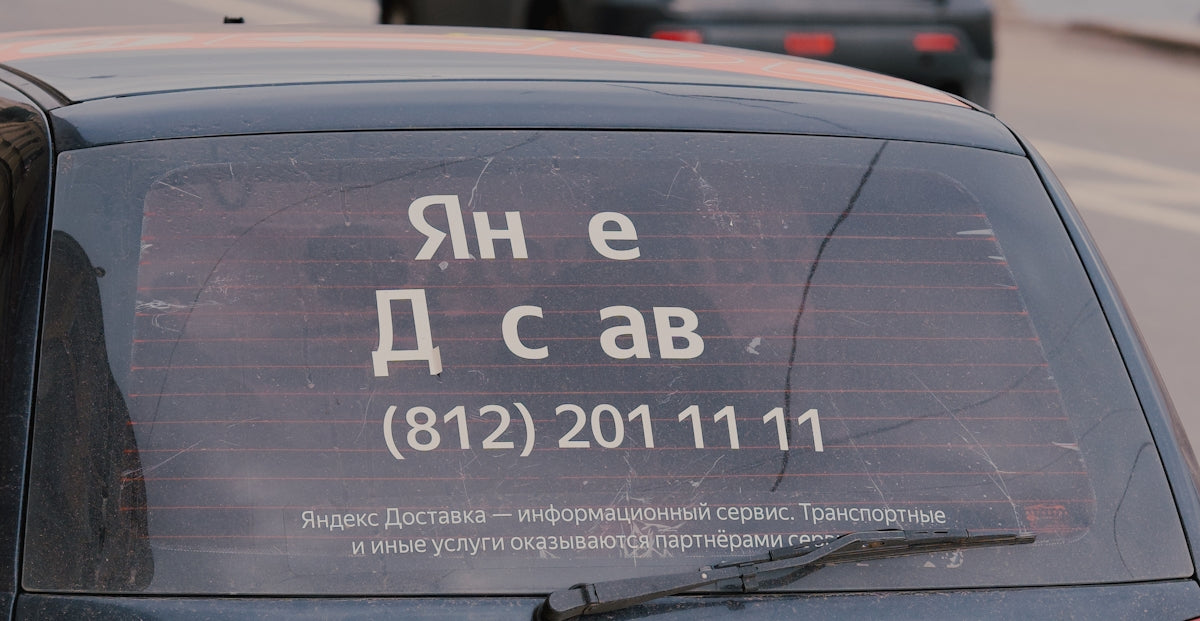 Russian text and a phone number are on a car.