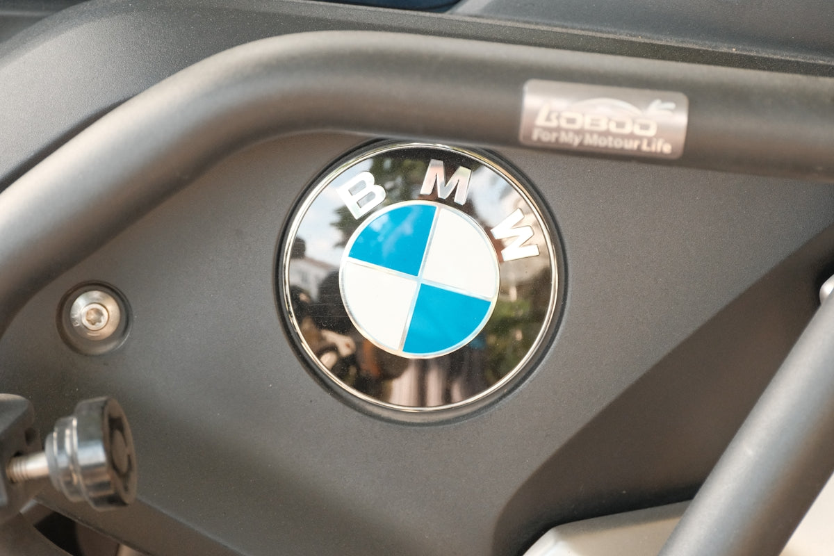 A close-up shows the BMW logo on a motorcycle.