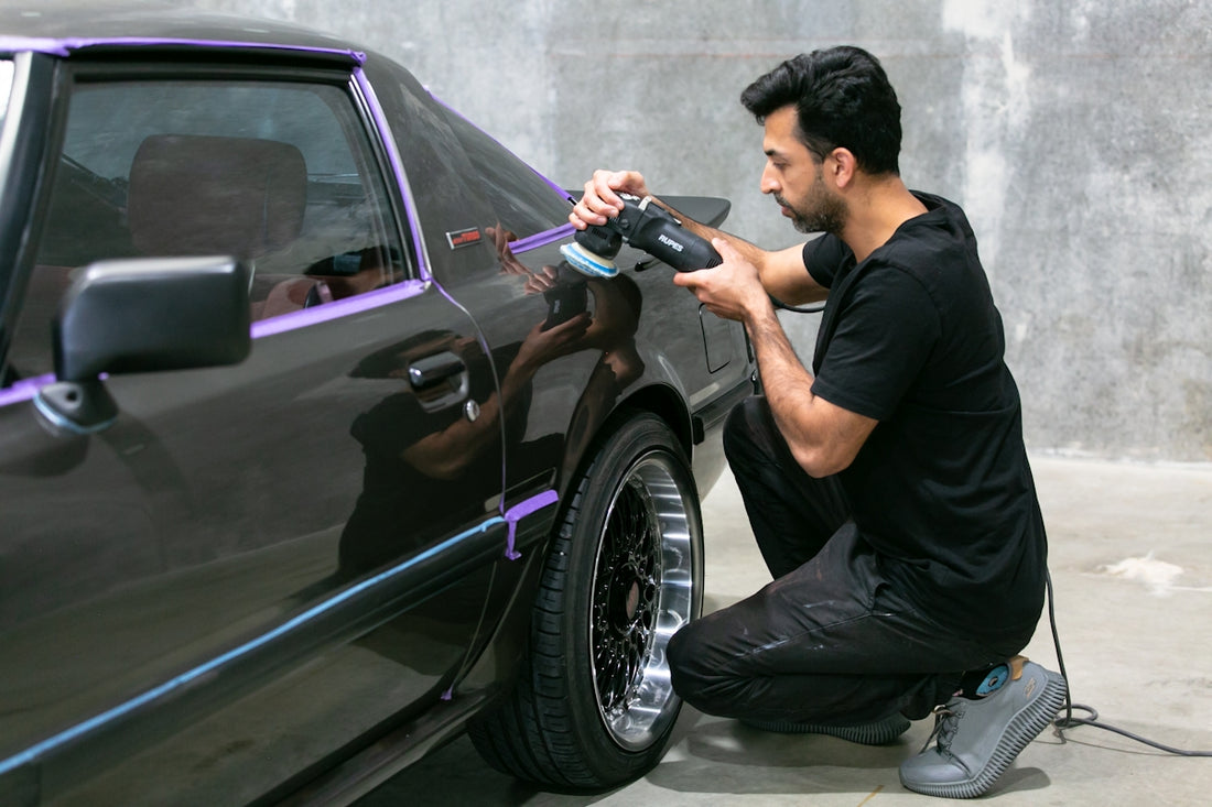 Man polishing a classic car's paintwork.