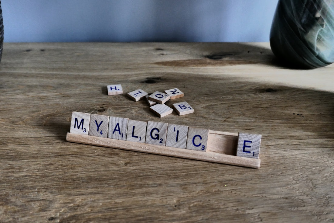 Scrabble tiles spell 'myalgic' on wooden surface