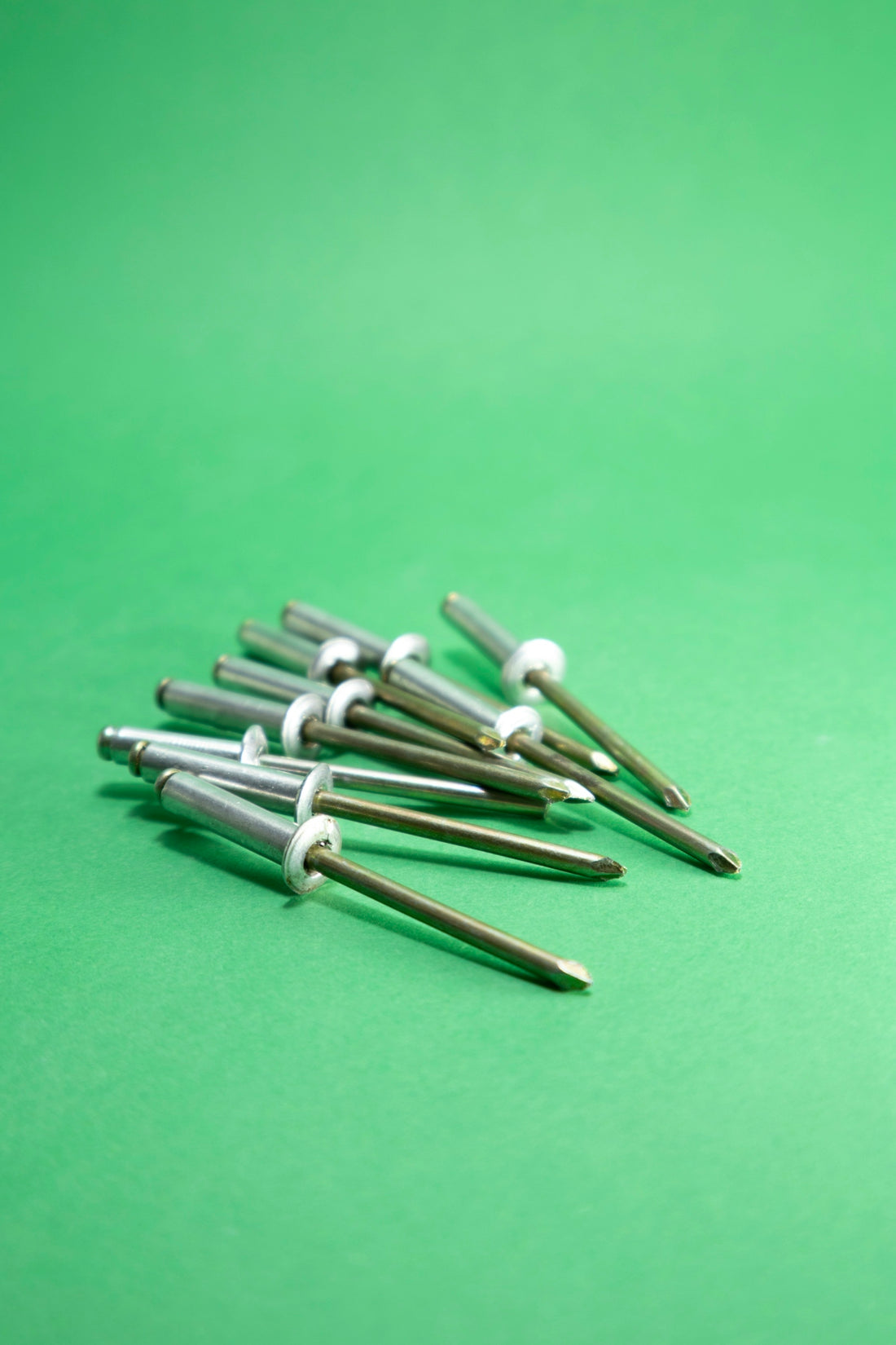 A pile of metal rivets on a green background