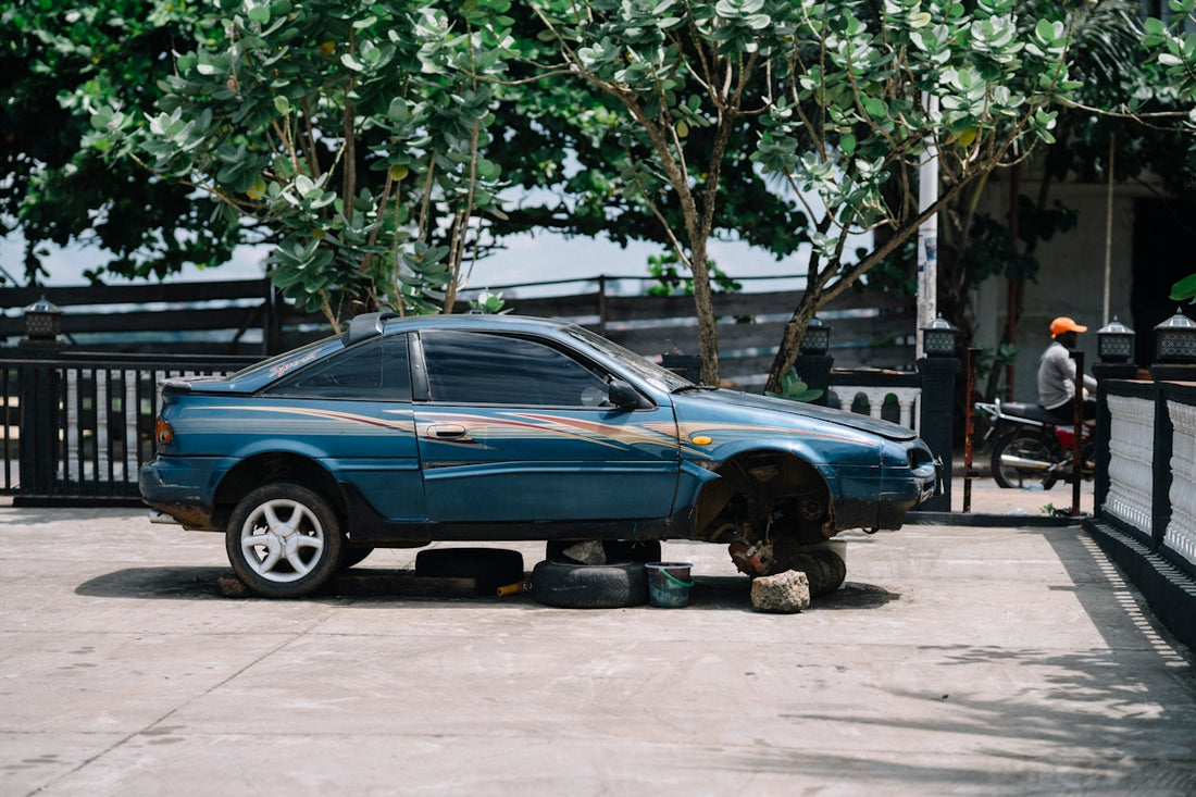 Blue car with wheels removed sits on blocks
