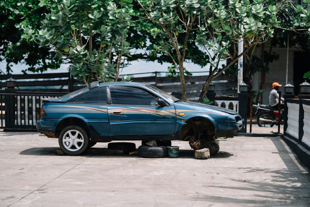 Blue car with wheels removed sits on blocks